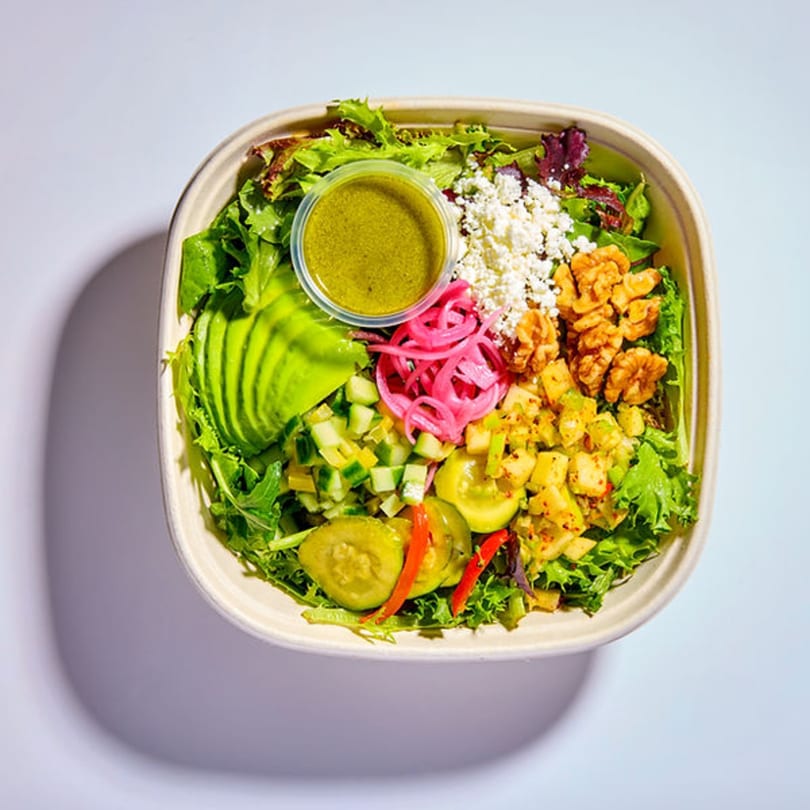 Vitasana healthy salad with avocado, feta, walnuts, pickled onions, and green dressing.